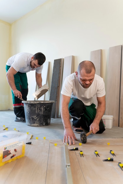 Full shot men tiling floor