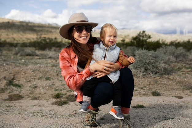 Foto bambino della holding della madre del colpo pieno nel deserto americano