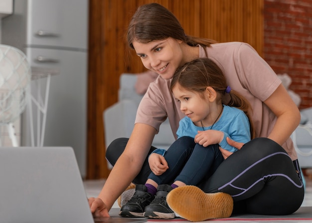 Full shot mother and kid looking at laptop