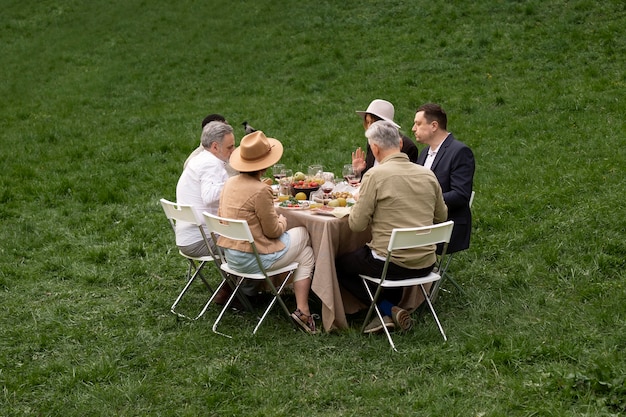 Full shot people eating in nature