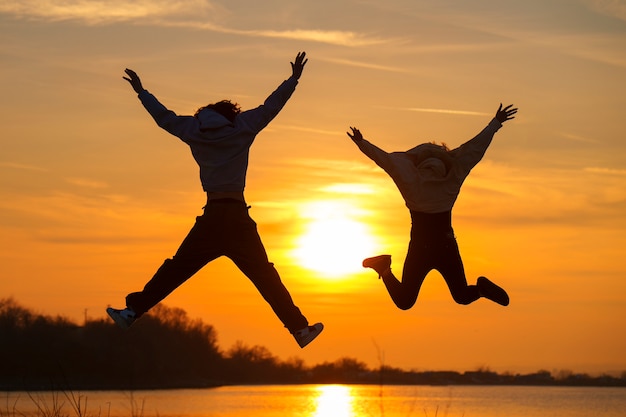 Full shot people jumping at sunset