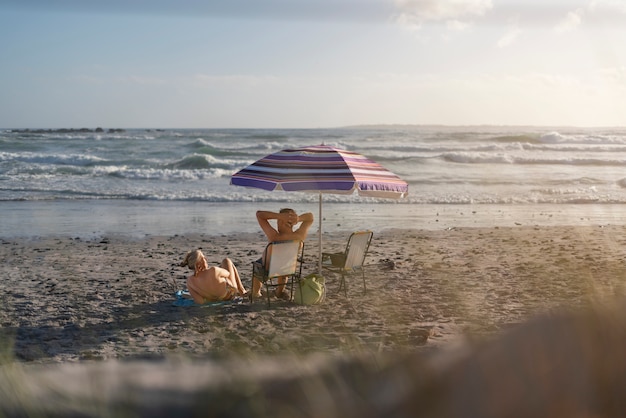 Foto coppia senior del colpo pieno che si siede alla spiaggia