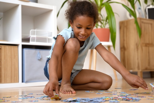 Foto ragazza sorridente del colpo pieno che fa puzzle sul pavimento