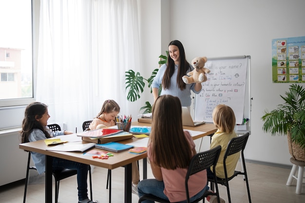 Photo full shot smiley teacher holding teddy bear