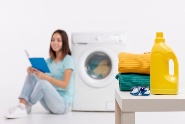 Full shot smiley woman reading and doing laundry