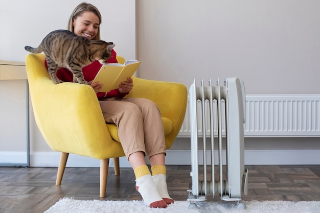 Donna sorridente del colpo pieno che legge con il gatto