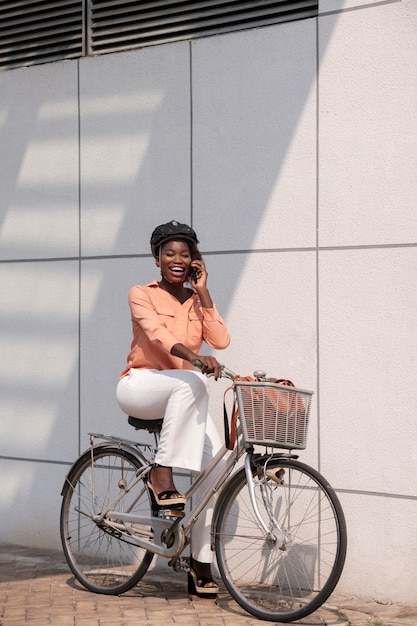 Foto donna sorridente del colpo pieno con la bicicletta ed il casco