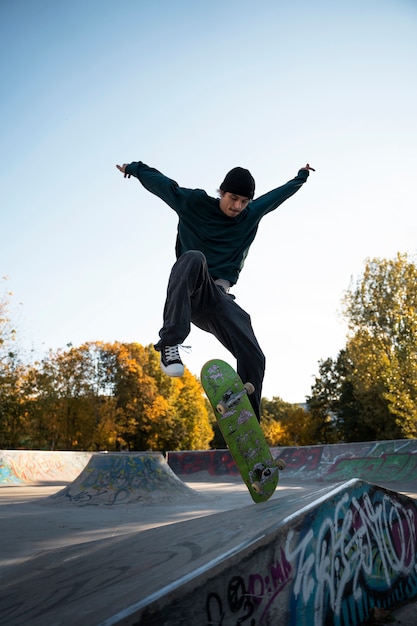 Foto adolescente a tutto campo che fa acrobazie sullo skateboard all'aperto