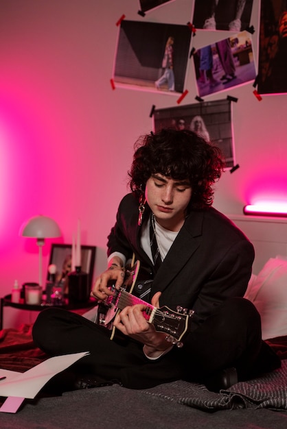 Foto adolescente a tutto campo che suona la chitarra al chiuso