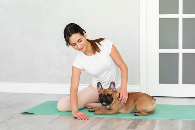 Full shot teenager and dog on yoga mat