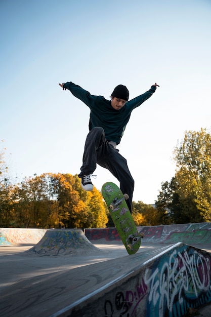 Foto full shot tiener doet trucs op skateboard buitenshuis