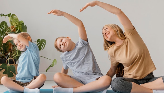 Full shot woman and children exercising