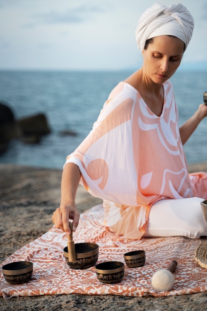 Full shot woman on cloth with singing bowls