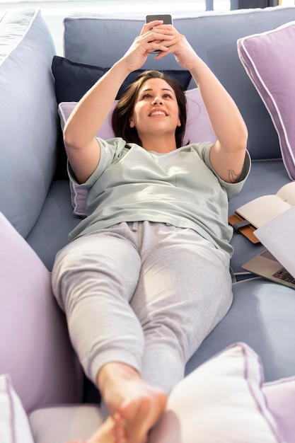 Photo full shot woman on couch with phone