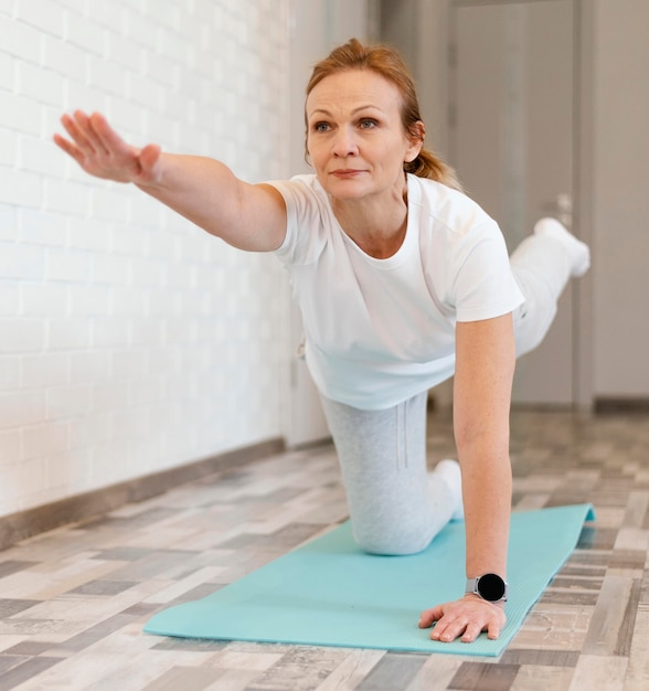 Foto donna piena del colpo che fa yoga sulla stuoia
