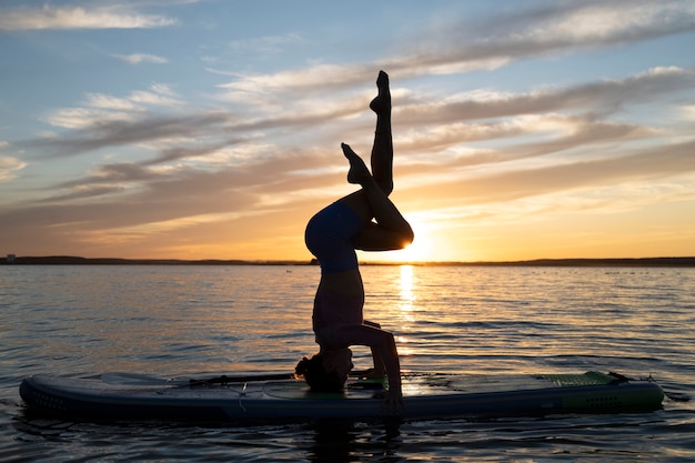 Foto donna a tutto campo che fa yoga in riva al mare