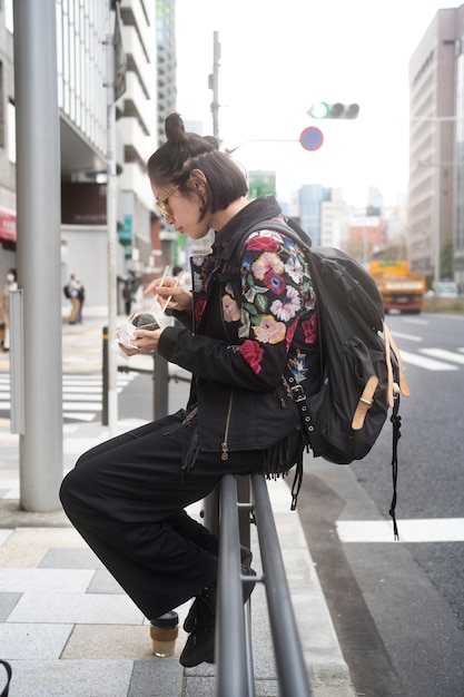 日本の屋台の食べ物を食べるフルショットの女性