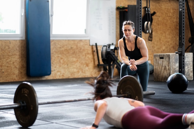 写真 トレーナーと運動するフルショットの女性