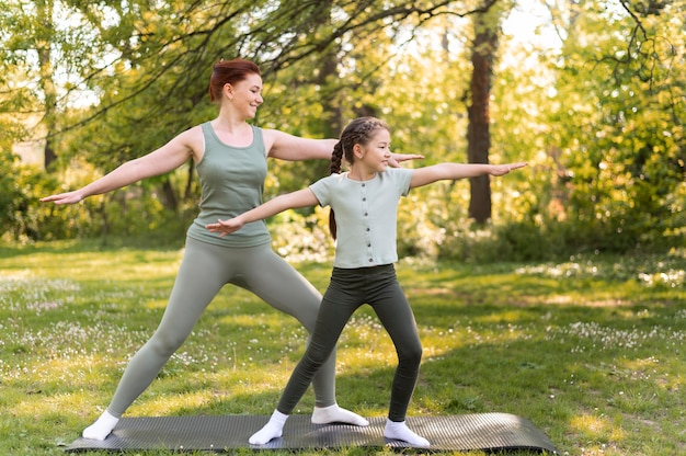 Colpo completo donna e ragazza sulla stuoia di yoga