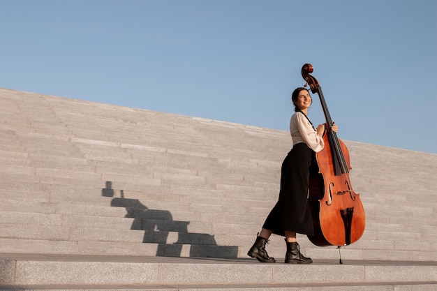 Full shot woman holding double bass