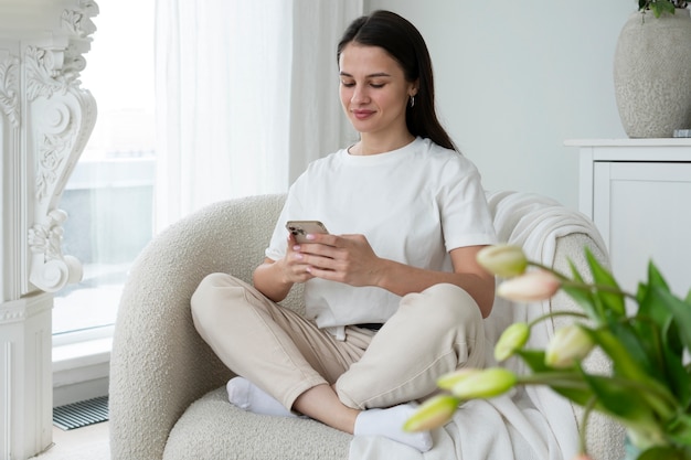 Full shot woman holding smartphone