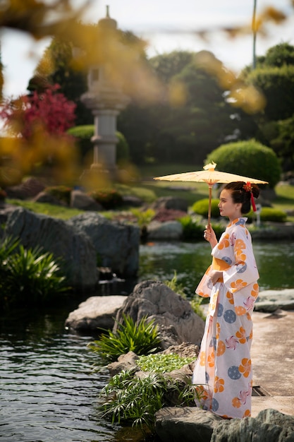 写真 屋外で和傘を持ったフルショットの女性