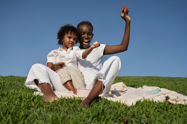 Foto donna e bambino del colpo pieno che si siedono sull'erba