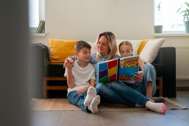 Полный кадр женщина и дети читают комиксы в помещении