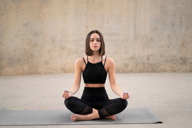 Full shot woman meditating on yoga mat