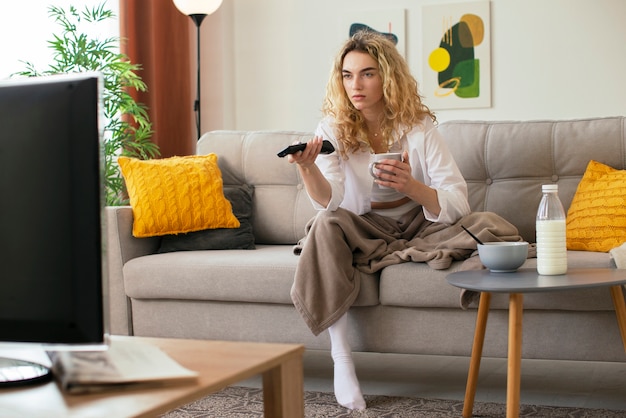 テレビを見ているソファの上のフルショットの女性