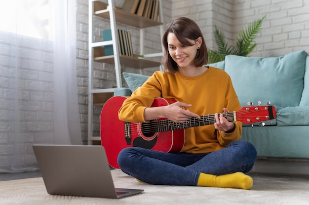 Full shot woman playing guitar with laptop