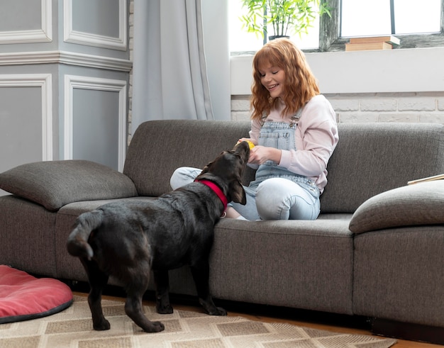 Full shot woman playing with dog indoors