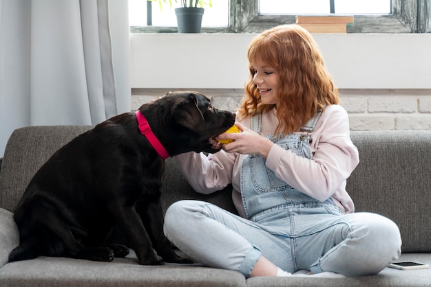 ソファで犬と遊ぶフルショットの女性