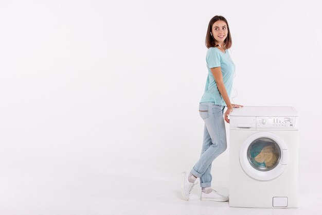 Full shot woman posing near washing machine