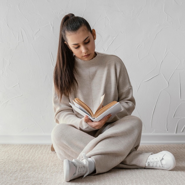 Full shot woman reading on floor