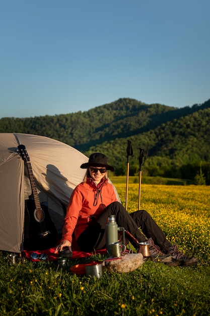 Foto donna a tutto campo seduta vicino alla tenda