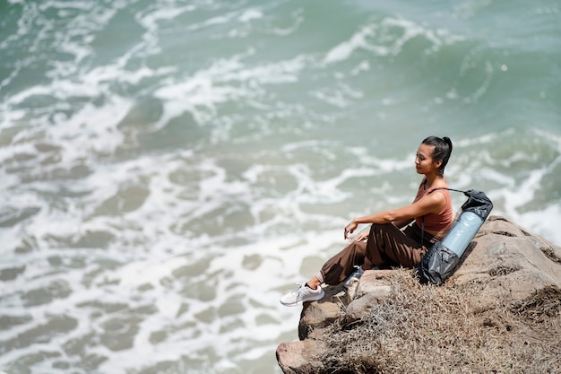 写真 岩の上に座っているフルショットの女性