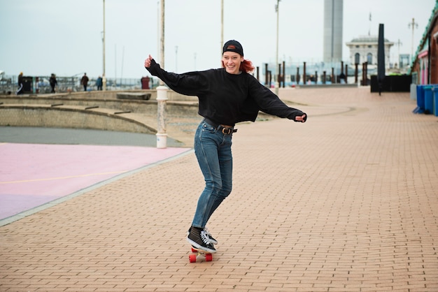 Женщина в полный рост на скейтборде на открытом воздухе