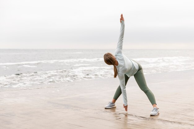 Full shot woman stretching at beach