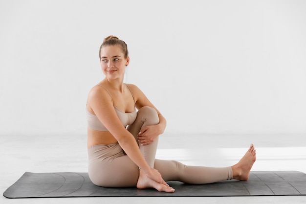 Full shot woman stretching on mat