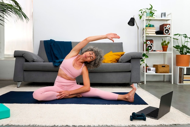 Foto donna della foto a figura intera che allunga sulla stuoia di yoga