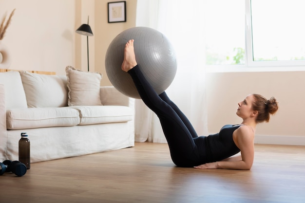 Foto donna a tutto campo che si allena con la palla da ginnastica a casa