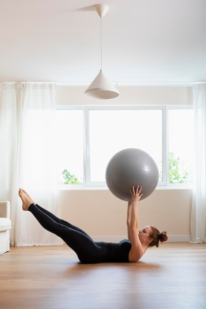 Foto donna a tutto campo che si allena con la palla da ginnastica