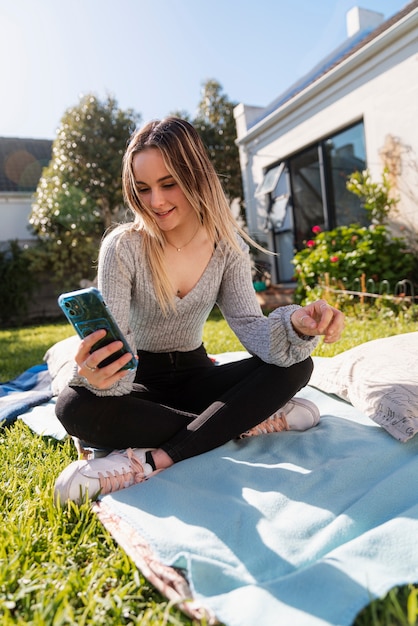 Foto donna a tutto campo che utilizza lo smartphone all'aperto