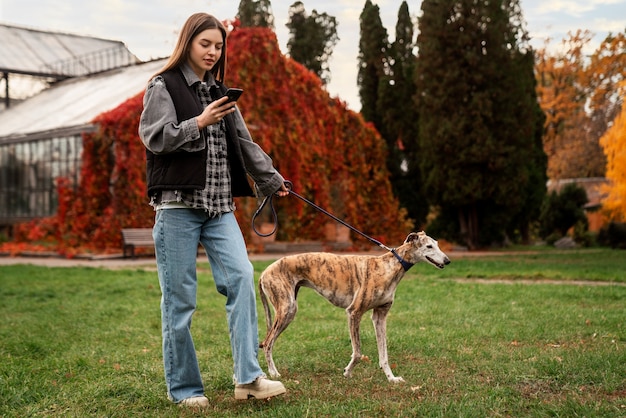 写真 かわいい犬を歩くフルショットの女性