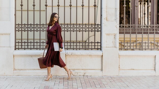 Full shot woman walking with laptop