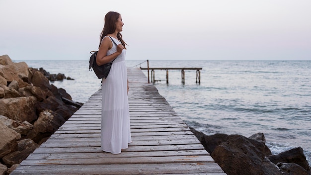 Foto donna piena del colpo che indossa un abito bianco