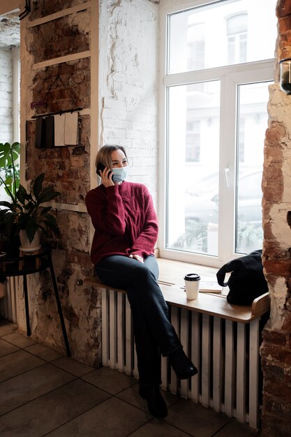 Full shot woman with mask talking on phone