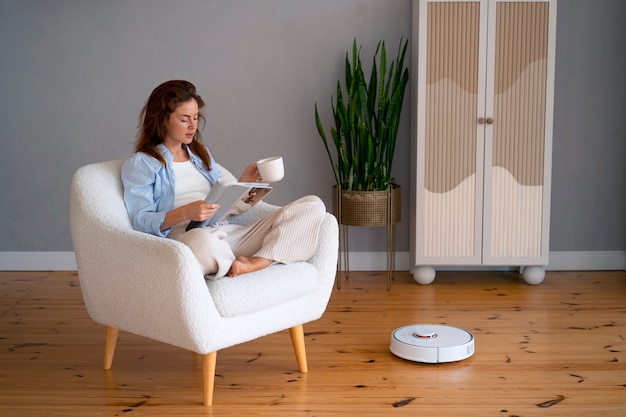 Photo full shot woman with  robotic vacuum cleaner