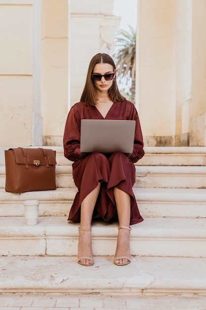 Foto donna piena del colpo che lavora al computer portatile